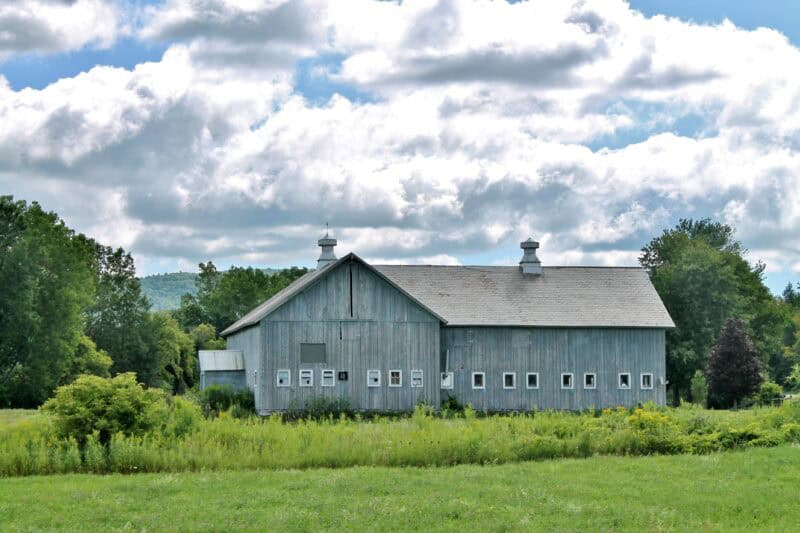 Gray barn, green grass, puffy clouds