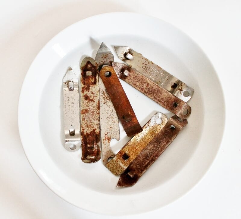 Rusty can openers soaking in vinegar in a white bowl