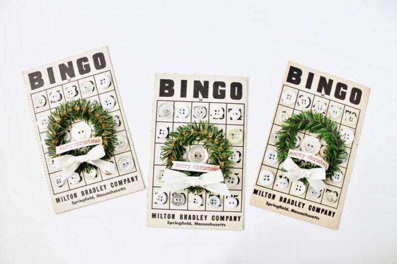 3 antique bingo cards decorated with white buttons and a mini wreath