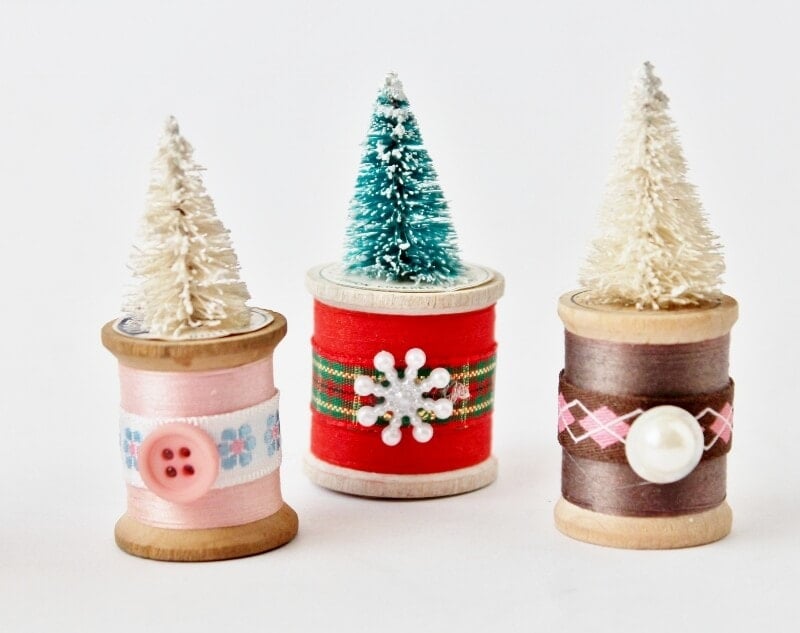 pink, red, and brown spools of thread with bottle brush trees on top