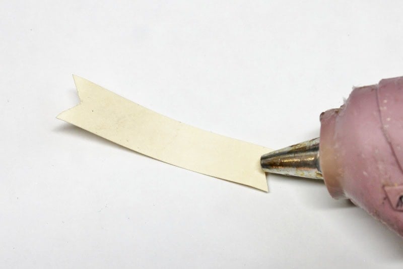 applying hot glue to the back of a tag