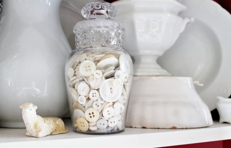 Jar of white buttons next to antique white ironstone
