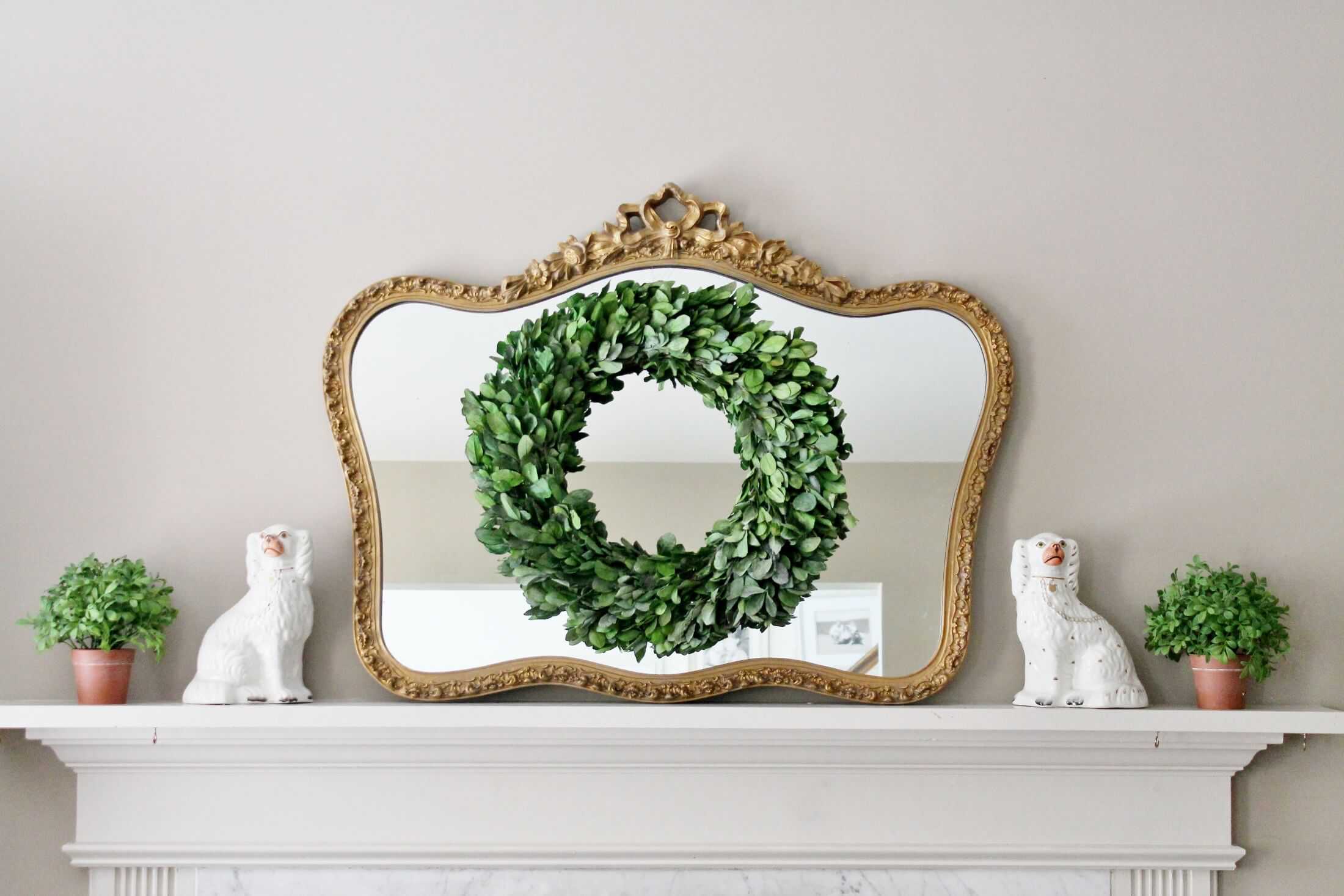 boxwood wreath hanging on vintage gold gilt mirror