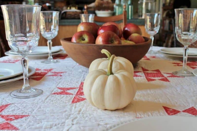 fall table with white pumpkins, apples, and quilt
