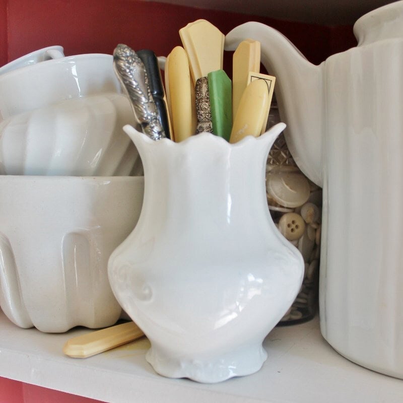 antique button hooks displayed in antique ironstone jar in a cupboard with other ironstone