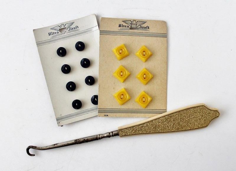 Antique glittery celluloid button hook below two cards of antique buttons