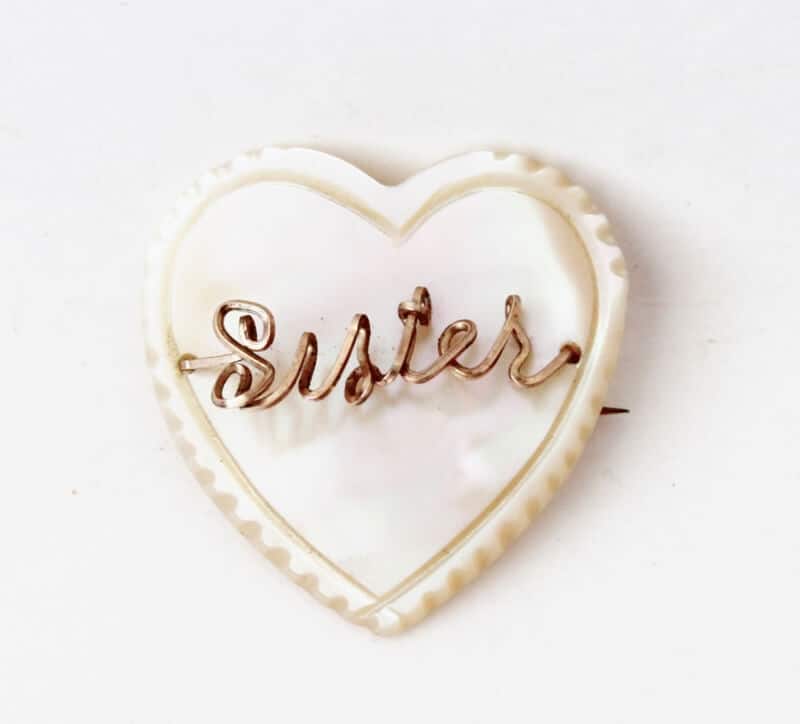 white heart with gold wire spelling "sister"
