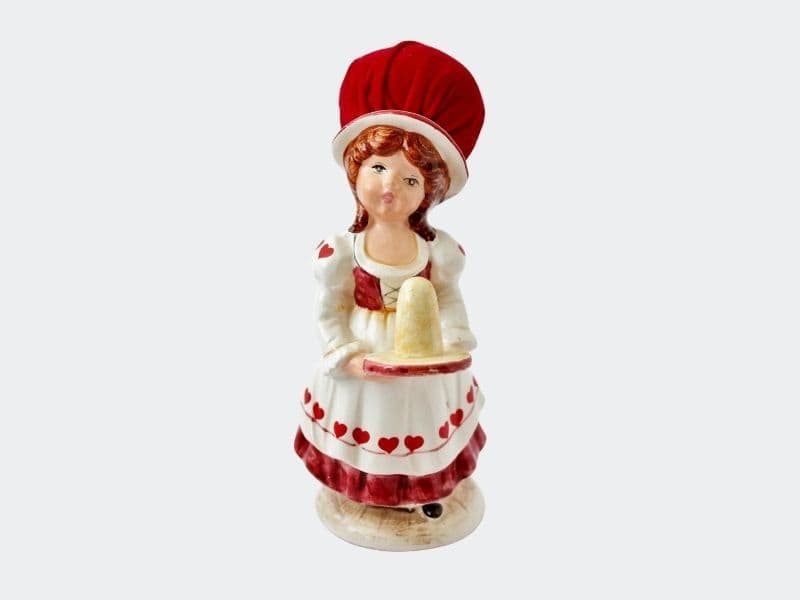 Vintage ceramic gilr pin cushion dressed in red and white with a red velvet hat to hold pins