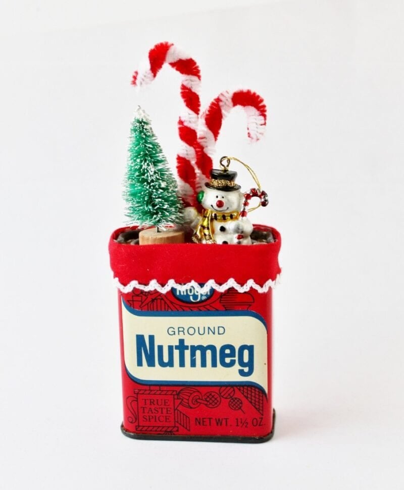 vintage nutmeg spice tin topped with Christmas diorama: snowman and bottle brush tree
