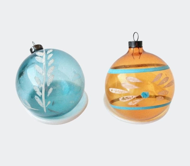 two glass ornaments with hand painted design one blue, one orange