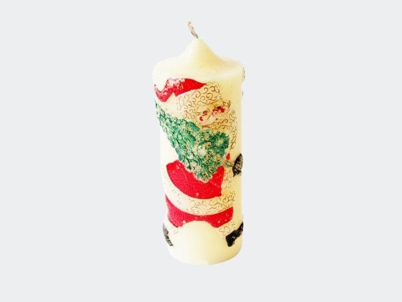 white pillar candle with santa on front holding a tree