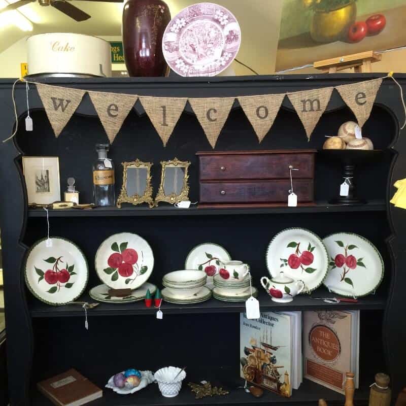 Antique booth: black shelf with dishes and welcome banner