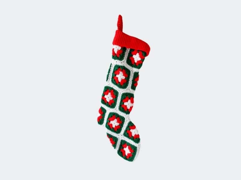 Festive crochet Christmas stocking featuring red, green, and white floral motifs, perfect for holida.
