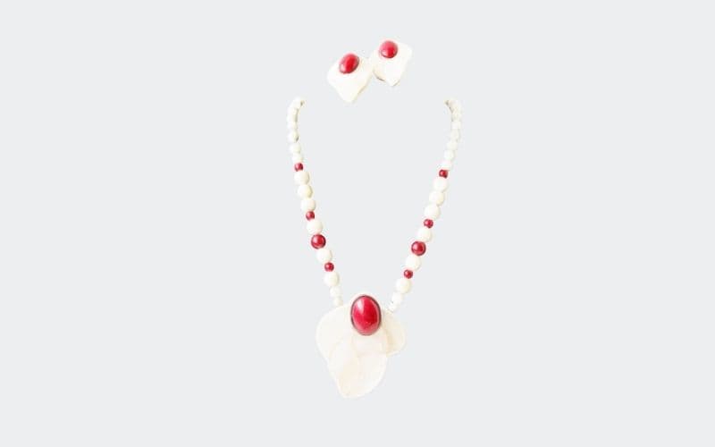white and red necklace with large pendant at center